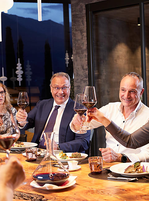 Mehrere Personen sitzen beim Tisch und amüsieren sich bei Getränken und Essen