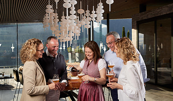 Die Gastgeberin schenkt den Gästen ein Glas Bier ein 